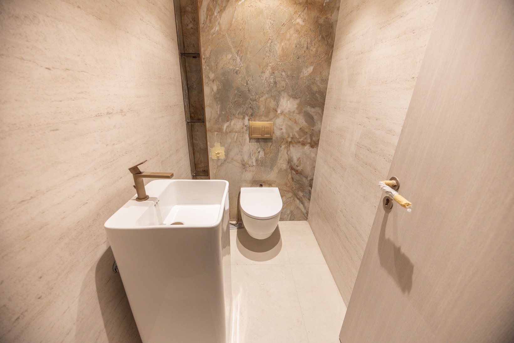 Pearl House By Imtiaz Modern bathroom featuring a sleek sink, wall-hung toilet, and elegant stone wall design with neutral tones.